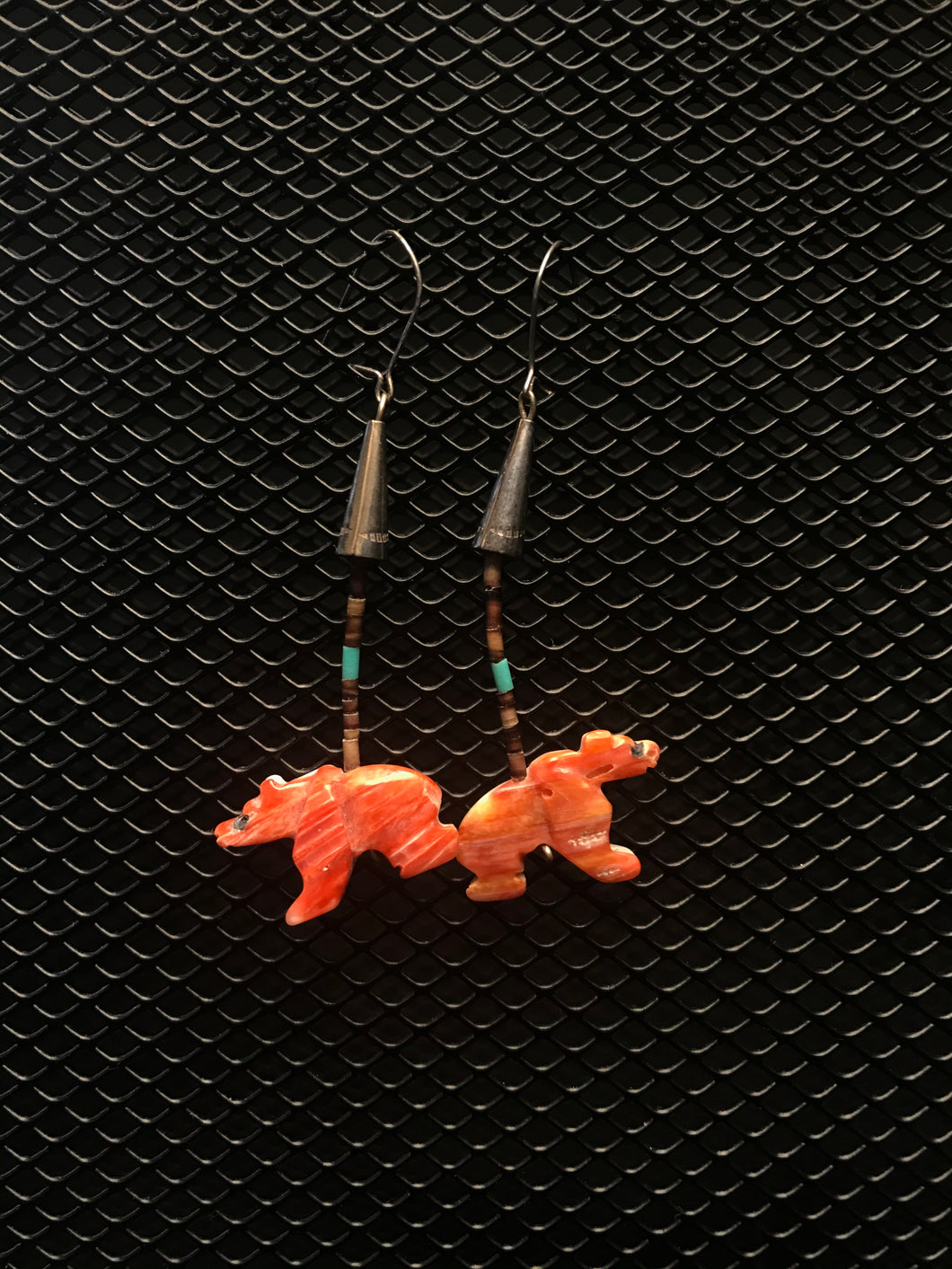 Silver colored hook earrings with coral colored bear fetish from spiny oyster.